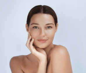 A woman with clear, glowing skin posing confidently, representing healthy skincare results.
