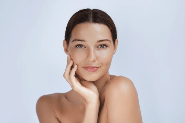A woman with clear, glowing skin posing confidently, representing healthy skincare results.